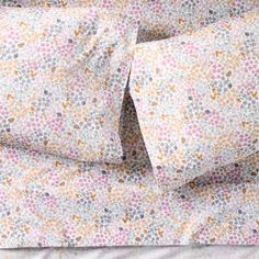 a bed with two pillow cases and one is made out of floral print fabric, while the rest of the sheets are folded down