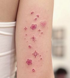 a woman's arm with tattoos on it and hearts, stars, and flowers