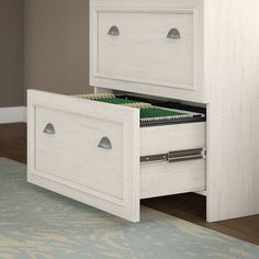 a white dresser with two drawers and a file cabinet in the bottom drawer is open