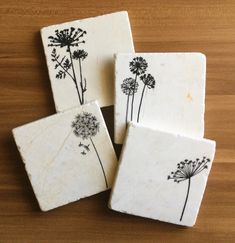 four coasters with dandelions drawn on them sitting on a table top next to each other