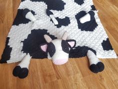 a black and white cow laying on top of a wooden floor next to a blanket