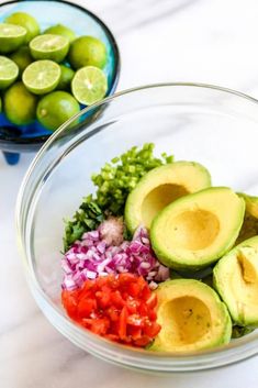 an avocado and red onion salad in a bowl with limes on the side