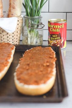 two hot dogs sitting on top of a baking pan next to some bread and garlic