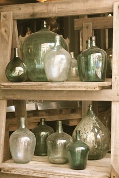 several green glass vases are sitting on wooden shelves