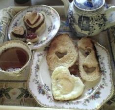 two plates with sandwiches and jam on them next to a cup of hot chocolate in a teapot