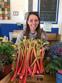 a woman sitting at a table with lots of carrots and flowers in front of her