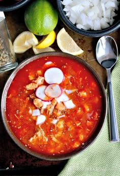 a bowl filled with soup next to two bowls of rice and limes on the side