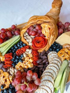 a platter filled with cheese, crackers, grapes and other food on top of a white table cloth