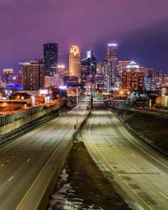 the city skyline is lit up at night, with traffic moving along it's sides