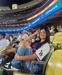 a woman sitting in the bleachers at a baseball game with her hand on her head