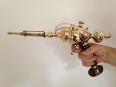 a person is holding an antique brass colored blow dryer in their right hand and it's attached to the wall