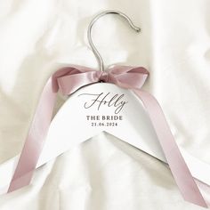 a white hanger with a pink ribbon on it that says, ally the bride