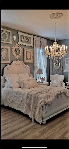 a bedroom with a bed, chandelier and pictures on the wall