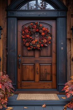 a wooden door with a wreath on the front and side of it, surrounded by fall foliage