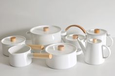 a group of white pots and pans with wooden handles