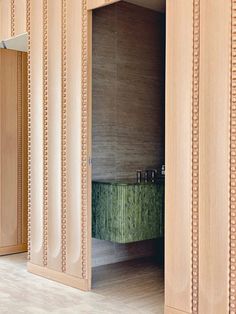 an open door leading into a bathroom with a green tub in the corner and wooden walls