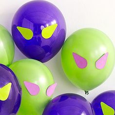 purple and green balloons with yellow eyes on them are arranged in the shape of cats