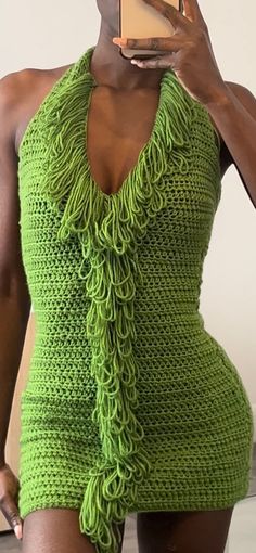 a woman taking a selfie while wearing a green knitted bodysuit and holding up a cell phone