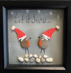 two birds wearing santa hats on top of rocks in a shadow box with the words let it snow