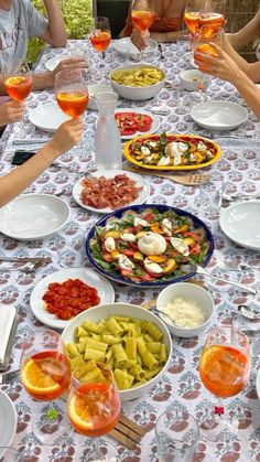 a group of people sitting around a table filled with food