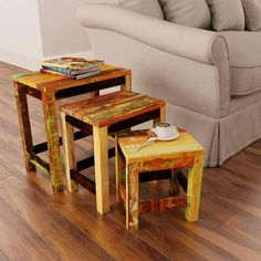 three wooden tables sitting on top of a hard wood floor next to a white couch