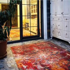 a large area rug is on the floor in front of an open glass door with a potted plant next to it