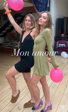 two beautiful young women standing next to each other holding pink and blue balloons in their hands