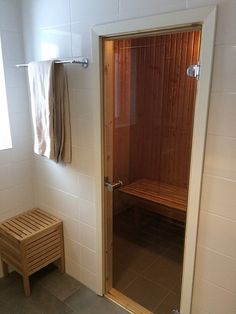 a wooden sauna in a white tiled bathroom