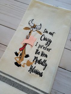 a white towel with an embroidered cow saying i'm not crazy