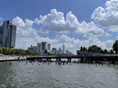 there is a bridge that goes over the water in front of some buildings and trees