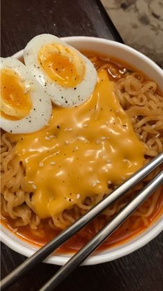 a bowl with noodles, eggs and chopsticks on it