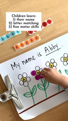 a child's hand writing on a paper with flowers and letters in the background