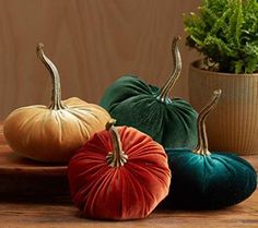 three velvet pumpkins sitting on top of a wooden table