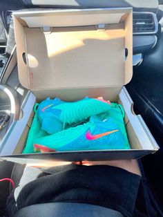 the inside of an open shoe box in someone's car with blue and pink shoes