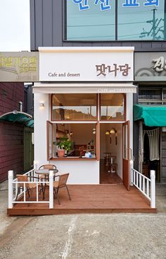 the outside of a small restaurant with tables and chairs in front of it's windows