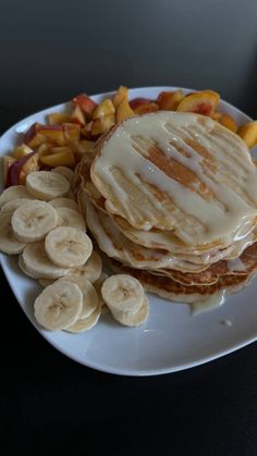 pancakes with bananas and syrup on a plate next to some sliced up banana's