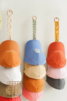 five hats hanging on hooks with chains attached to them, all in different colors and sizes