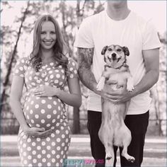 a man and woman standing next to each other with a dog on their belly in front of them