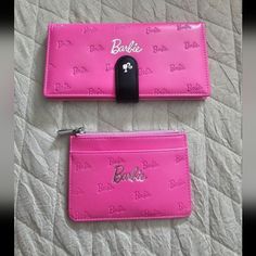 two pink wallets sitting on top of a bed