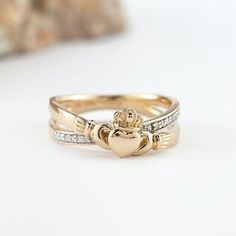 two gold clad hearts and crossbones ring with diamond accents on each band, set against a white background