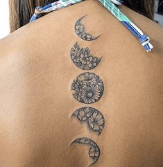 a woman's back with three phases of the moon and flowers on her lower back