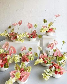 several white vases with pink and green flowers in them