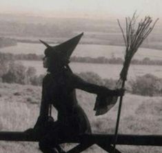 an old black and white photo of a woman dressed as a witch holding a broom