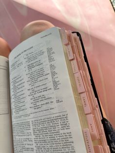 an open book sitting on top of a table next to a person holding a cell phone