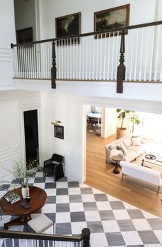 a living room with checkered flooring and white furniture in the middle of it