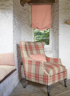 a chair sitting in front of a window with a checkered blanket on it's back