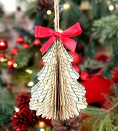 a book page christmas tree ornament hanging from a string with a red bow