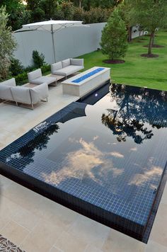 an outdoor swimming pool with lounge chairs and trees in the backgroung area