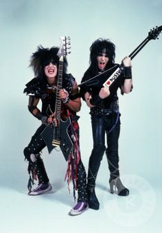 two women dressed in black holding guitars and posing for the camera with their mouths open