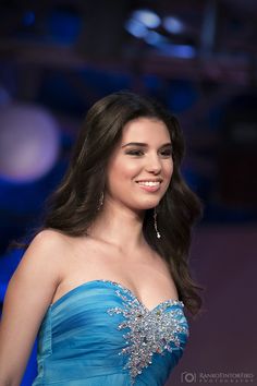 a woman in a blue dress smiles at the camera